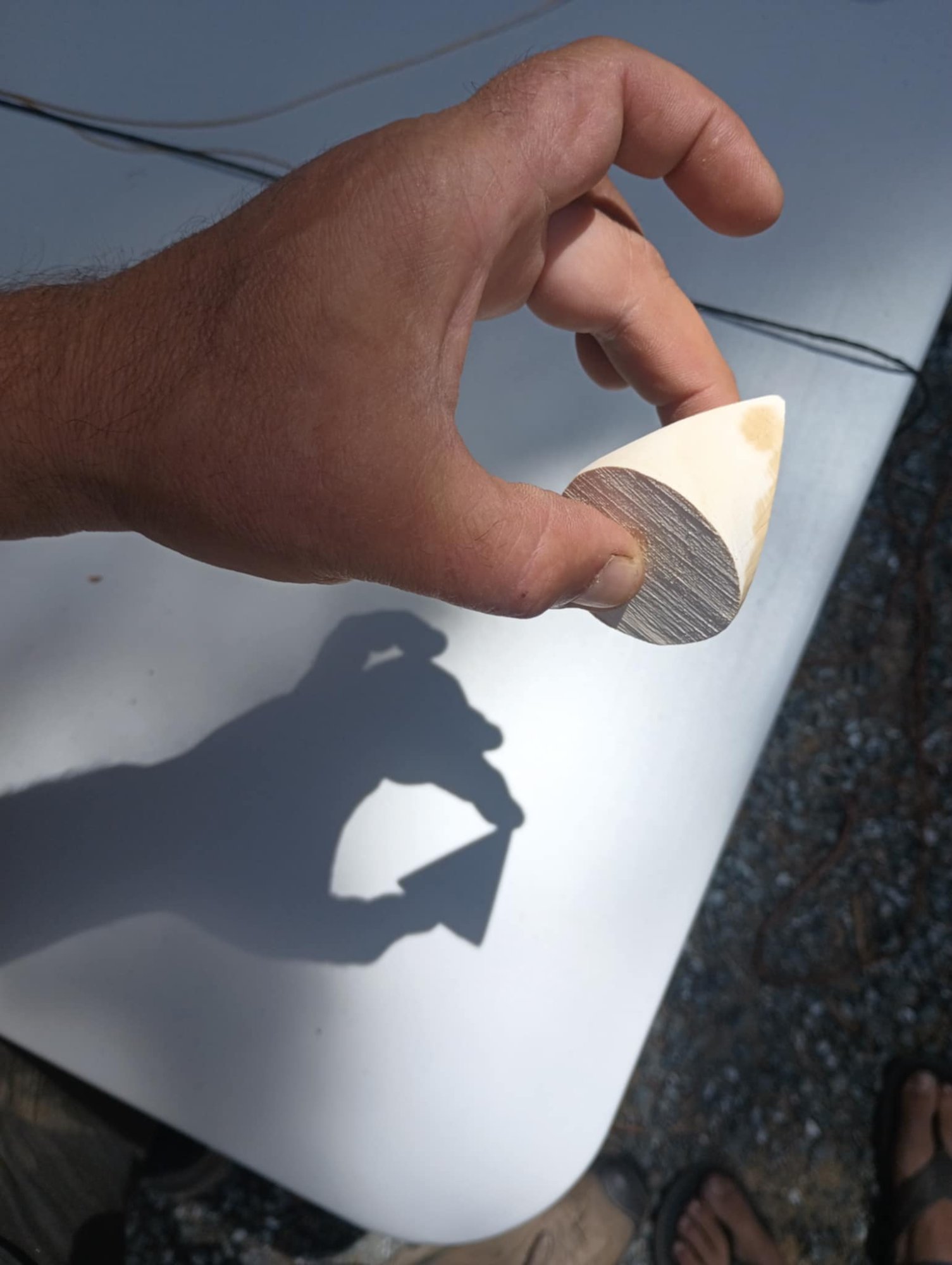 The skwedge held in sunlight casting a triangular shadow on a white surface
